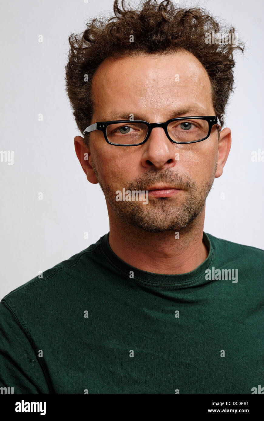 Un homme avec des lunettes, un t.shirt vert non rasé et Banque D'Images