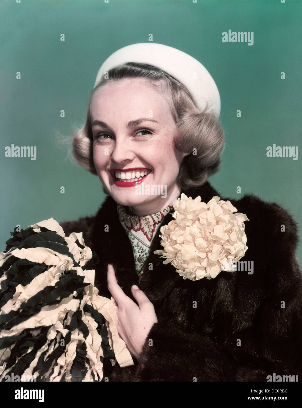 Années 1940 Années 1950 PORTRAIT SMILING BLOND WOMAN WEARING FUR COAT AVEC MAMAN DÉCORATION FLEUR POMPON HOLDING Banque D'Images
