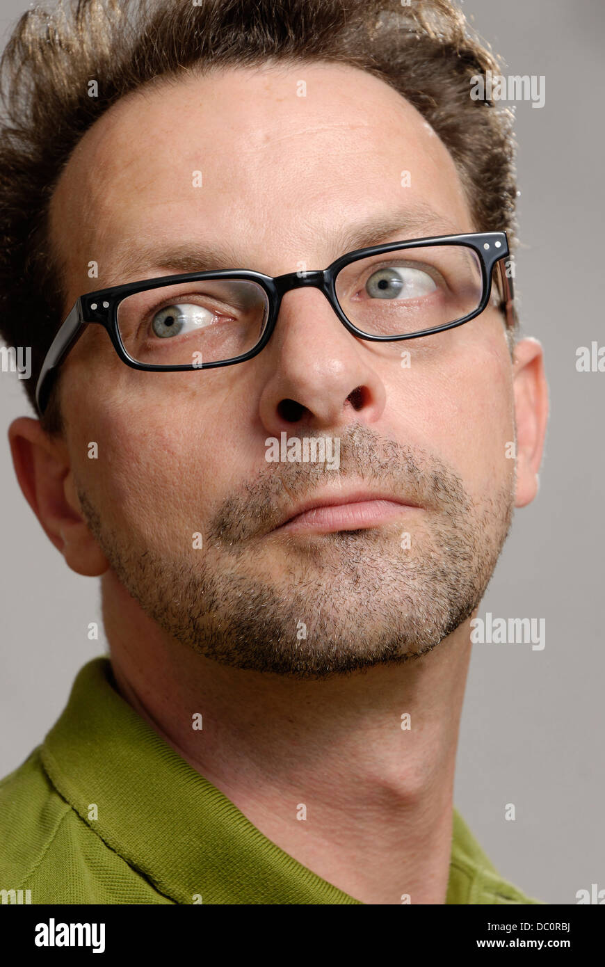 Un homme avec des lunettes, un polo vert non rasé et Banque D'Images