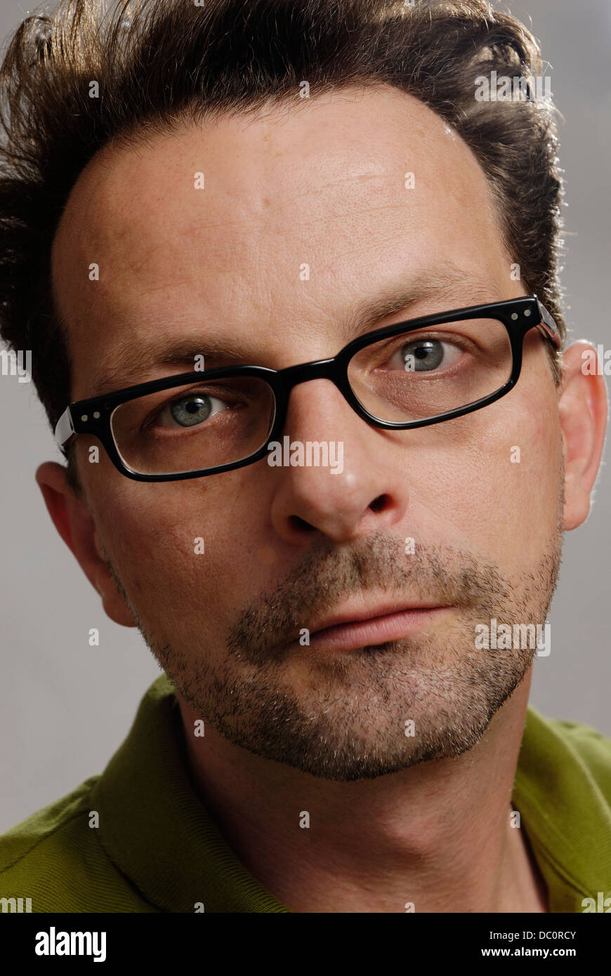 Un homme avec des lunettes, un polo vert non rasé et Banque D'Images