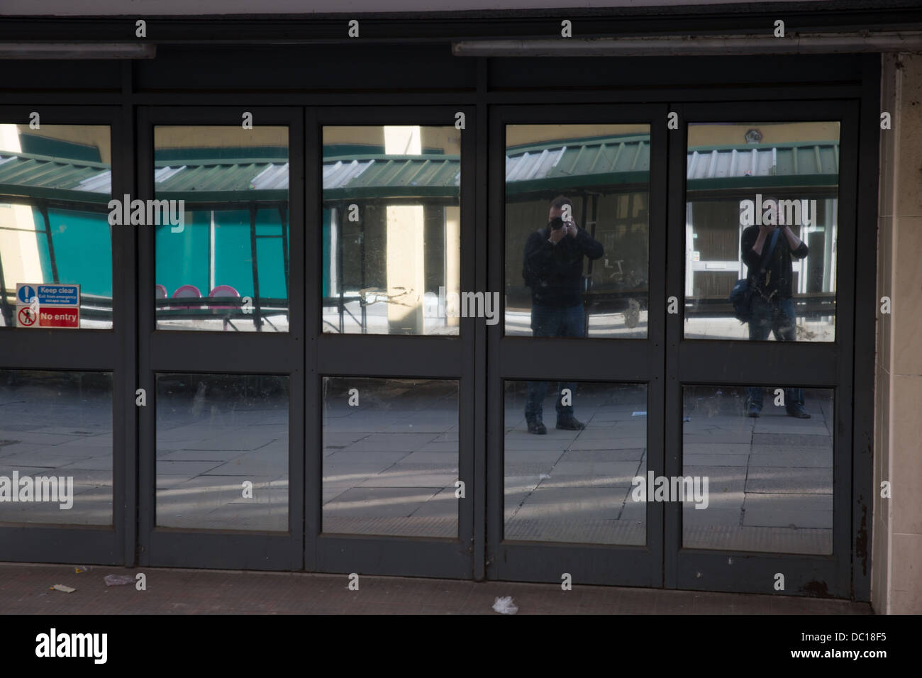 Deux photographes prendre une photo dans une vitrine rue réfléchissant Banque D'Images