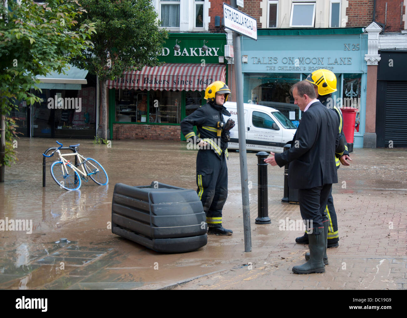 Londres, Royaume-Uni. 7e août 2013. Un propriétaire d'entreprise locale parle d'officiers alors qu'il tente d'avoir accès à sa propriété à la suite de l'inondation sur Half Moon Lane causé par une rafale d'eau principale qui conduit à des dommages de grande ampleur dans l'Herne Hill area of London Crédit : Andy Thornley/Alamy Live News Banque D'Images