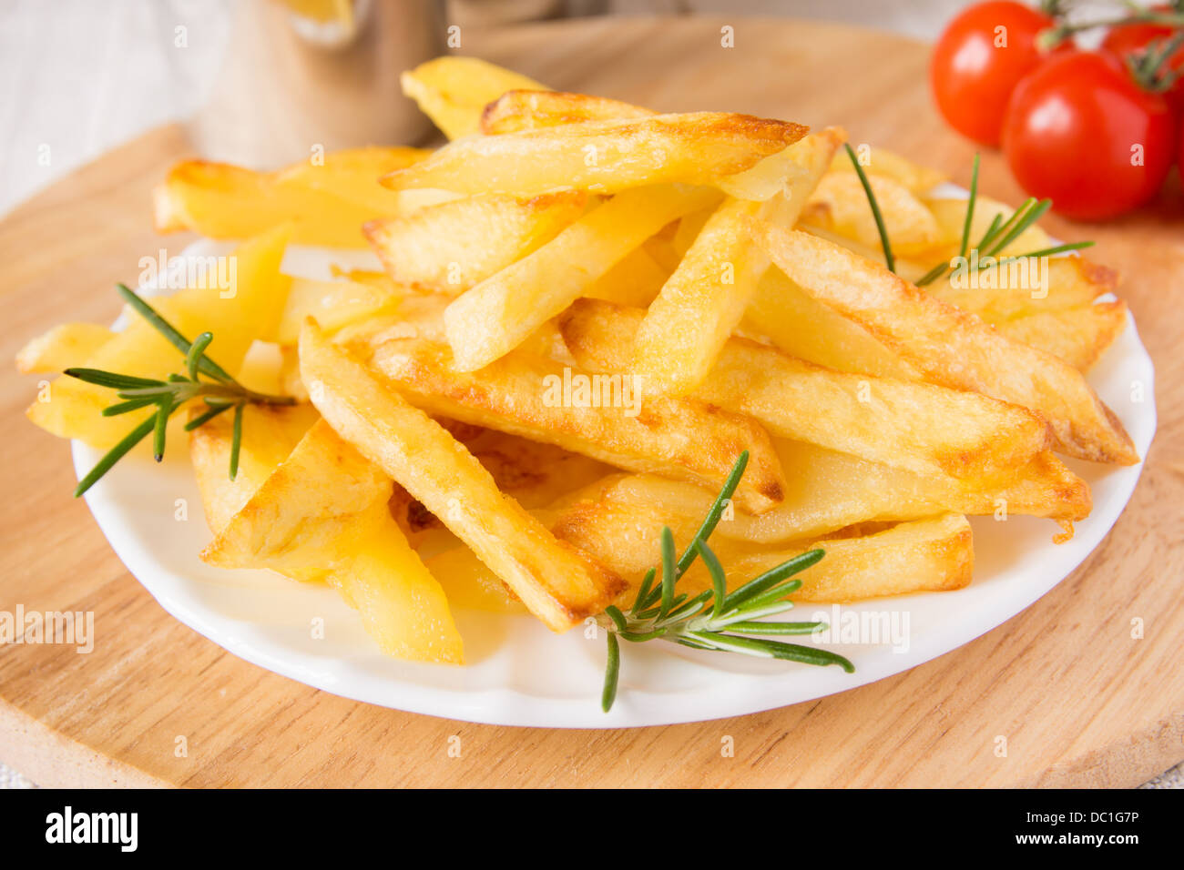 Portion de frites maison (pommes de terre) avec le romarin sur plaque blanche et planche à découper en bois, horizontal, Close up Banque D'Images