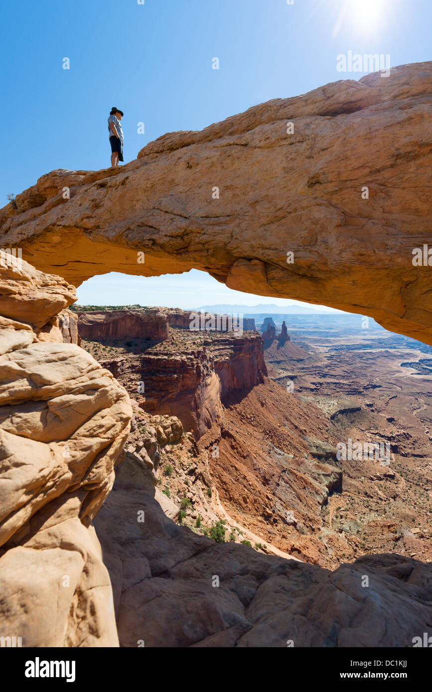 Walker debout sur Mesa Arch, Île dans le ciel, Canyonlands National Park, Utah, USA Banque D'Images