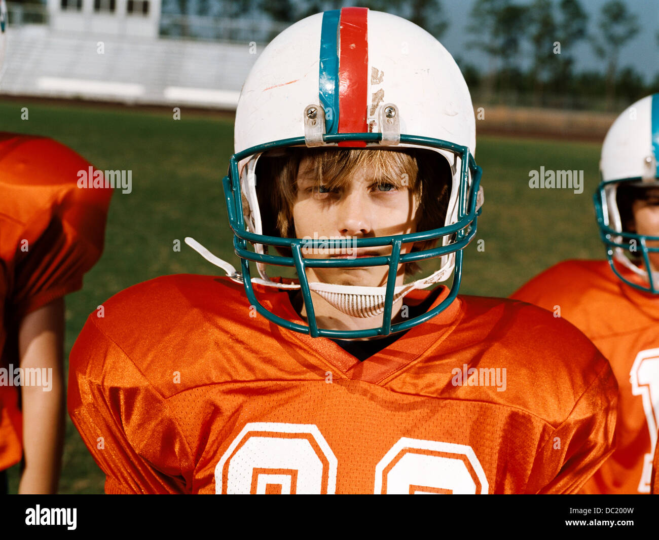 Boy wearing American football helmet, looking away Banque D'Images
