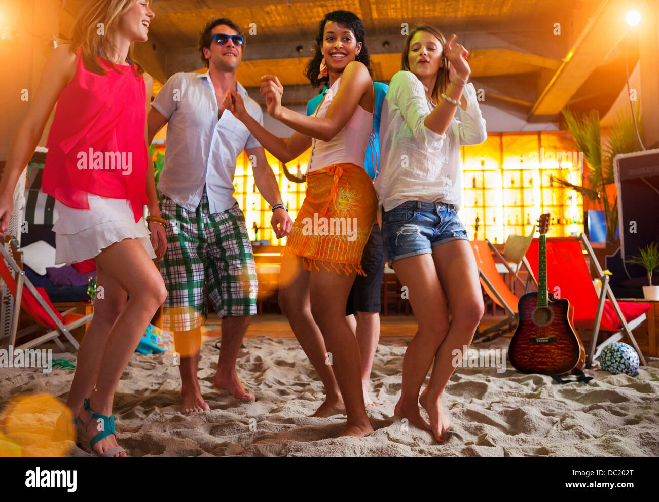 Les amis de la danse sur le sable à l'indoor beach bar Banque D'Images