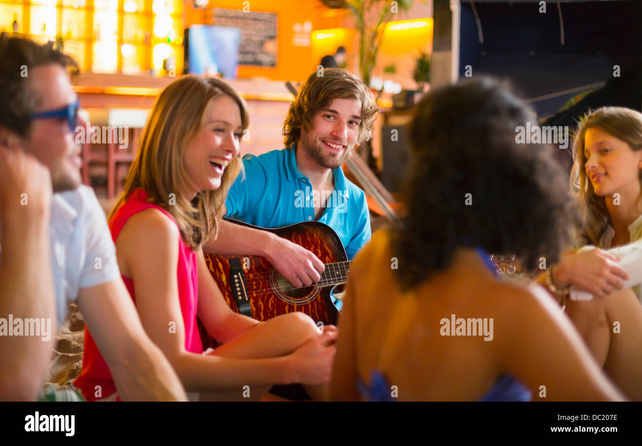 Bénéficiant d'amis pour son jeu de guitare en bar Banque D'Images