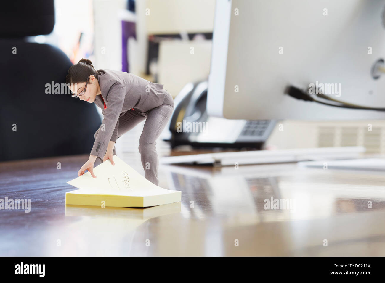 Businesswoman using large étiquette adhésive sur un immense bureau Banque D'Images