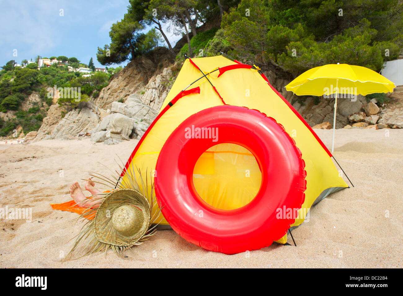 Jeter dans la plage jaune tente avec chapeau de paille et jouets gonflables Banque D'Images