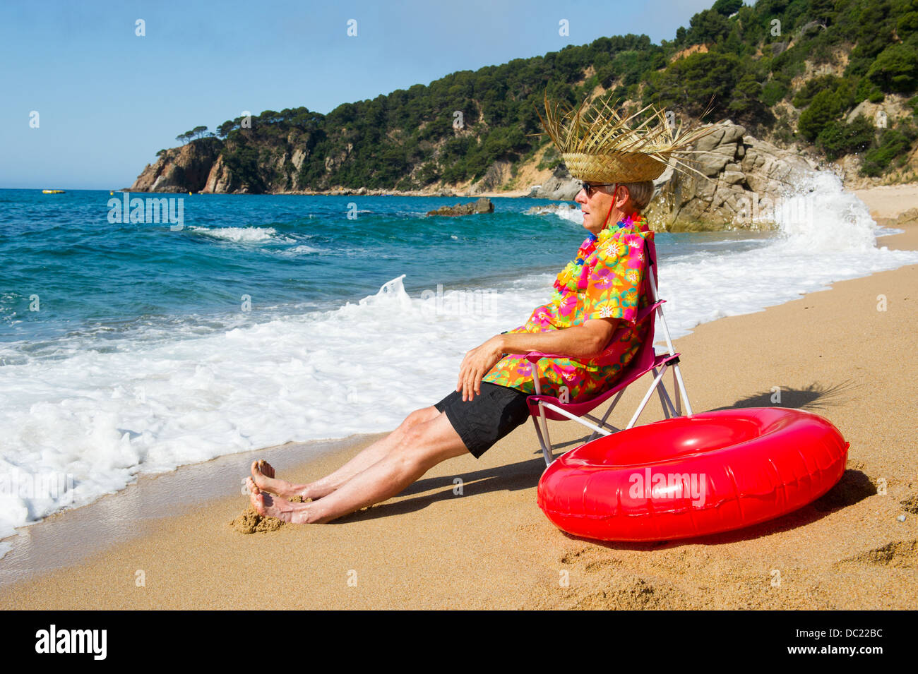 Senior man sitting in chair avec des jouets à la plage d'été Banque D'Images