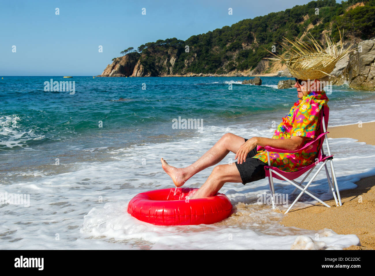 Senior man sitting in chair avec des jouets à la plage d'été Banque D'Images