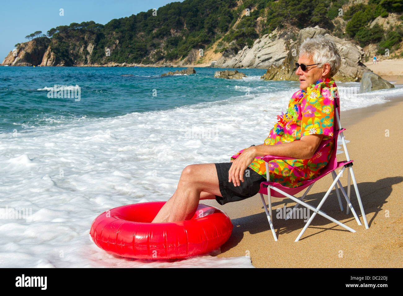 Senior man sitting in chair avec des jouets à la plage d'été Banque D'Images