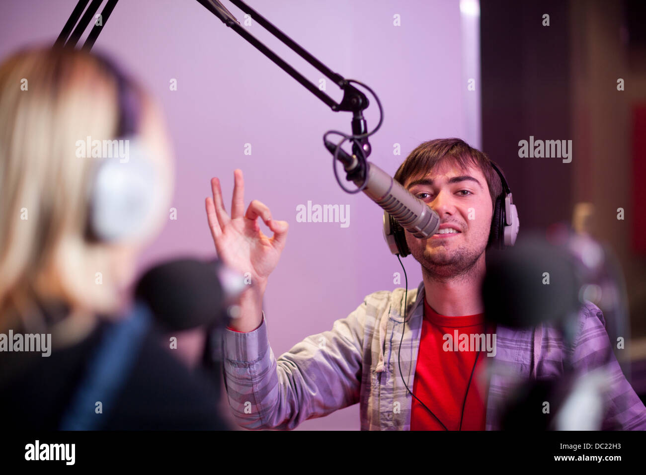Jeune homme et femme broadcasting in recording studio Banque D'Images