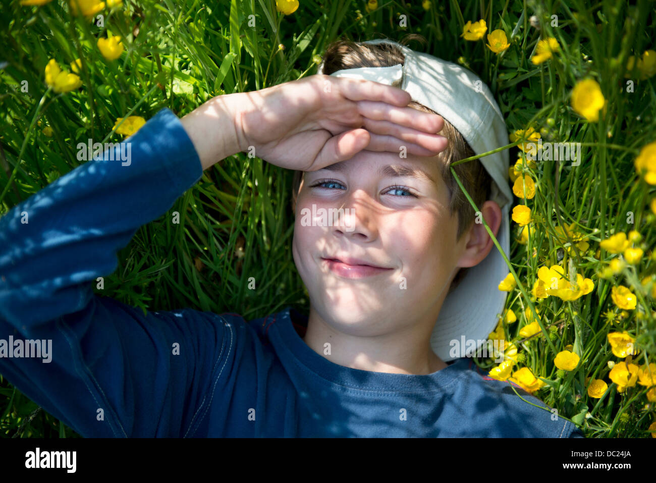 Boy lying on grass with hand on head Banque D'Images