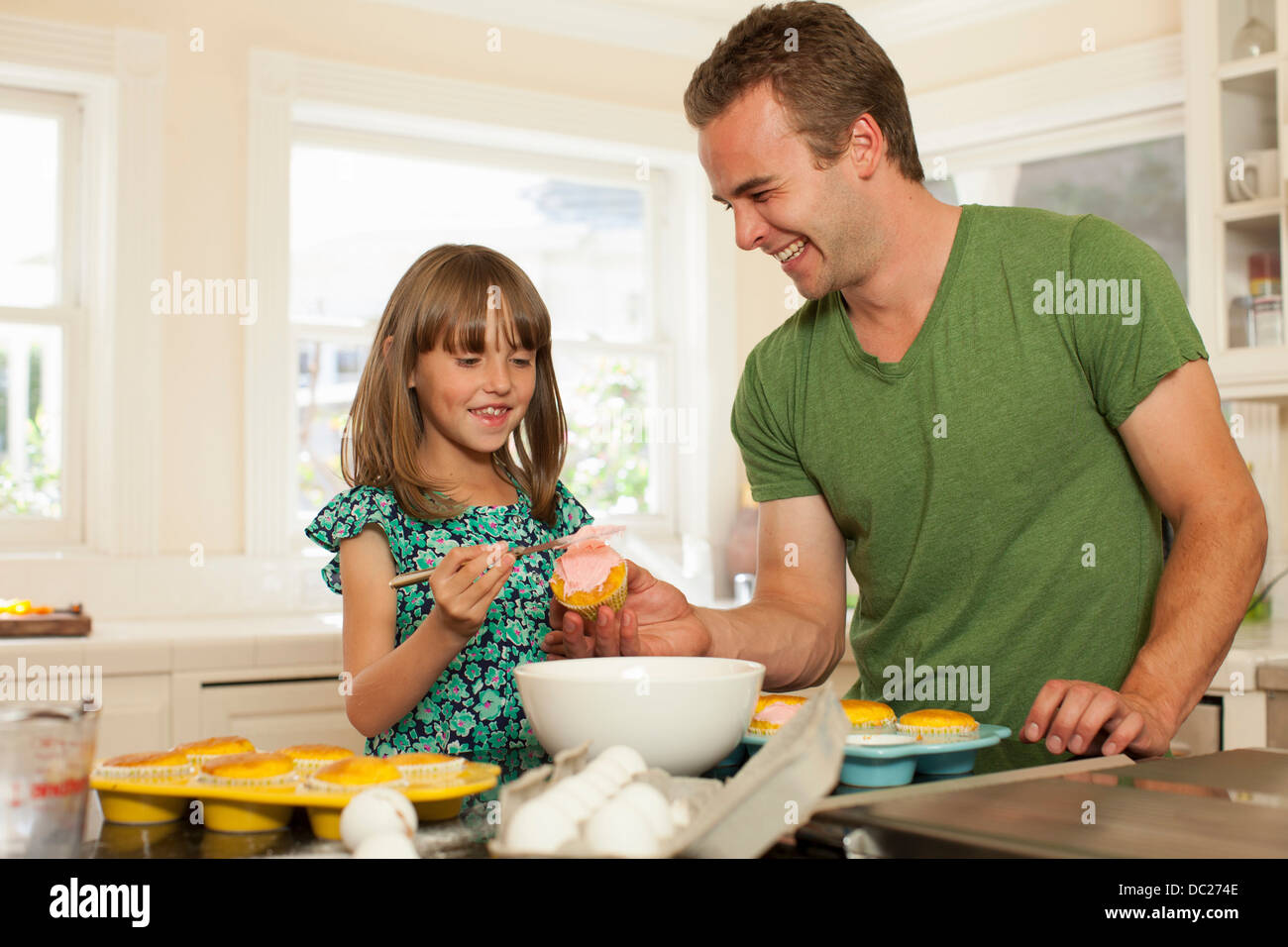 Jeune fille avec grand frère cupcakes glaçage Banque D'Images