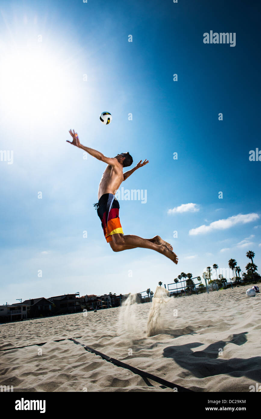 Joueur de volley-ball de plage hommes jumping mid air de frapper ball Banque D'Images