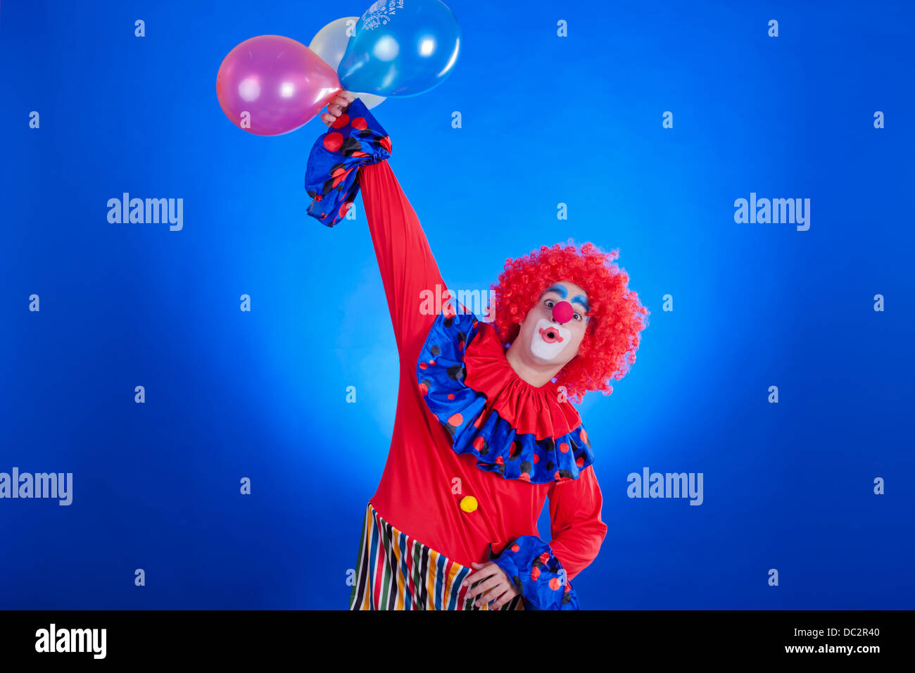 Happy clown avec ballon sur fond bleu à l'intérieur de studio shot Banque D'Images