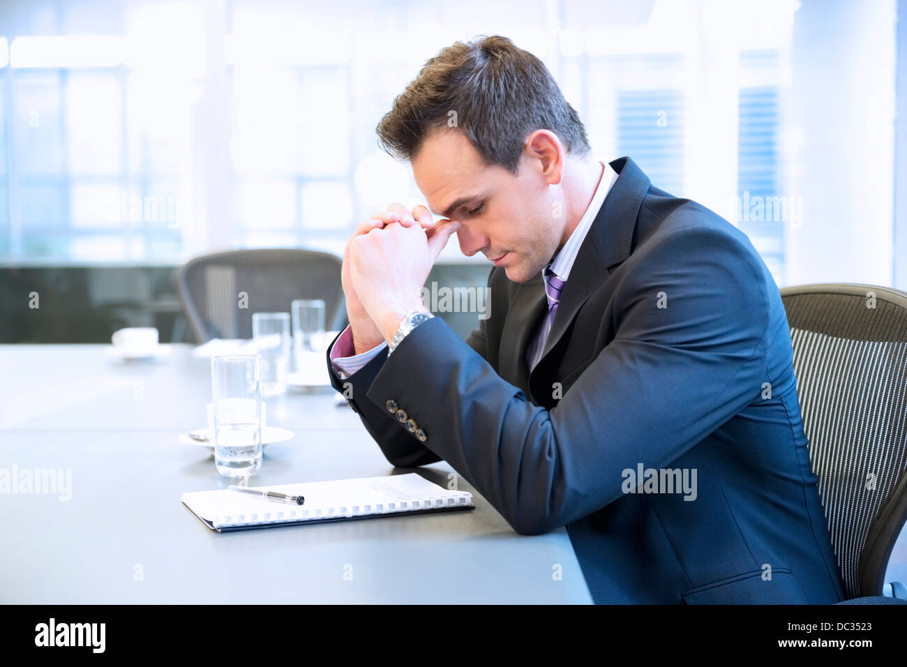 Businessman with head in hands in conference room Banque D'Images