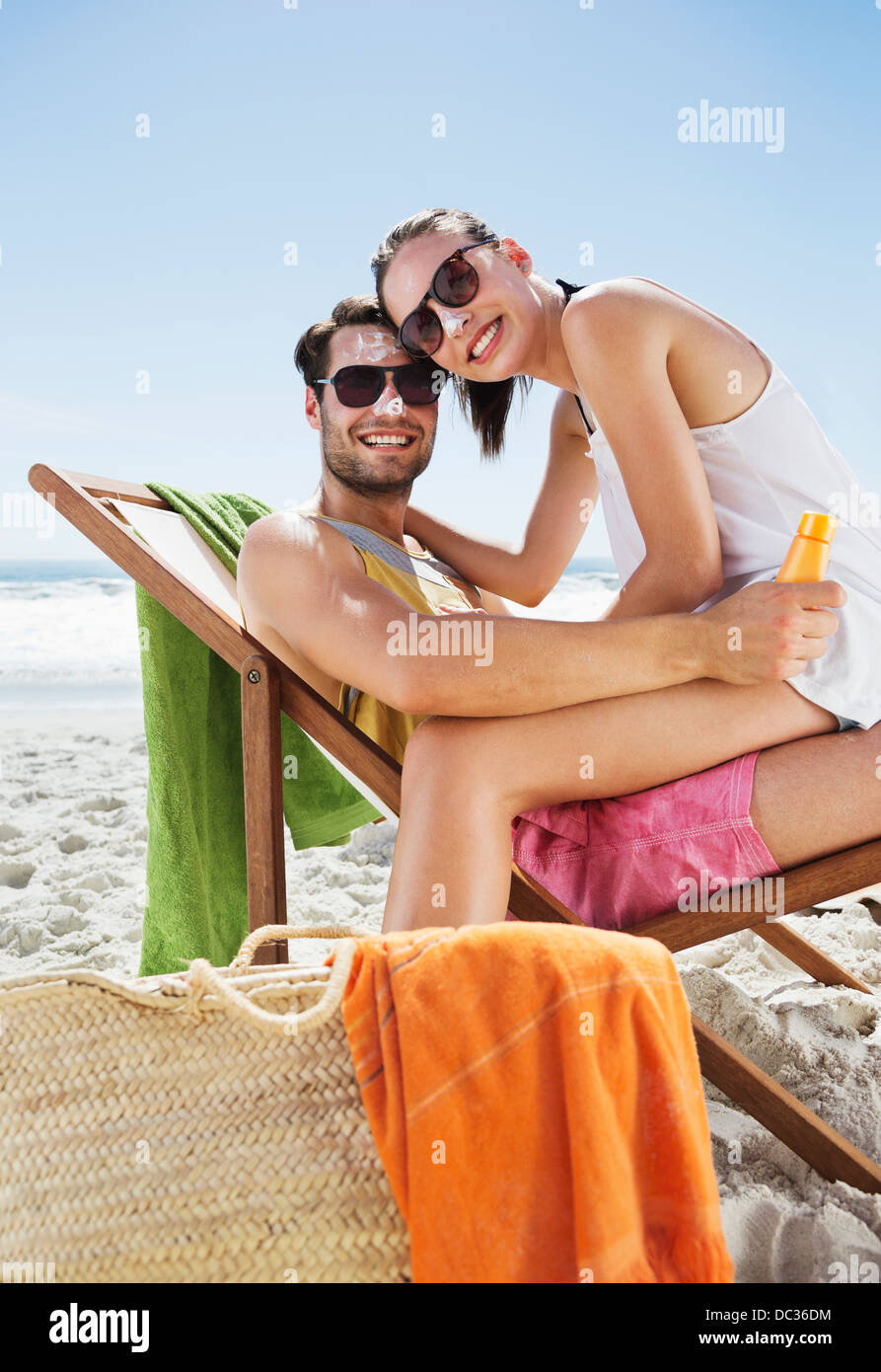 Portrait of smiling couple avec de la crème solaire sur la plage de nez Banque D'Images