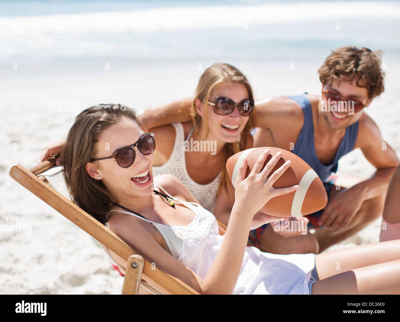Smiling friends with football on beach Banque D'Images