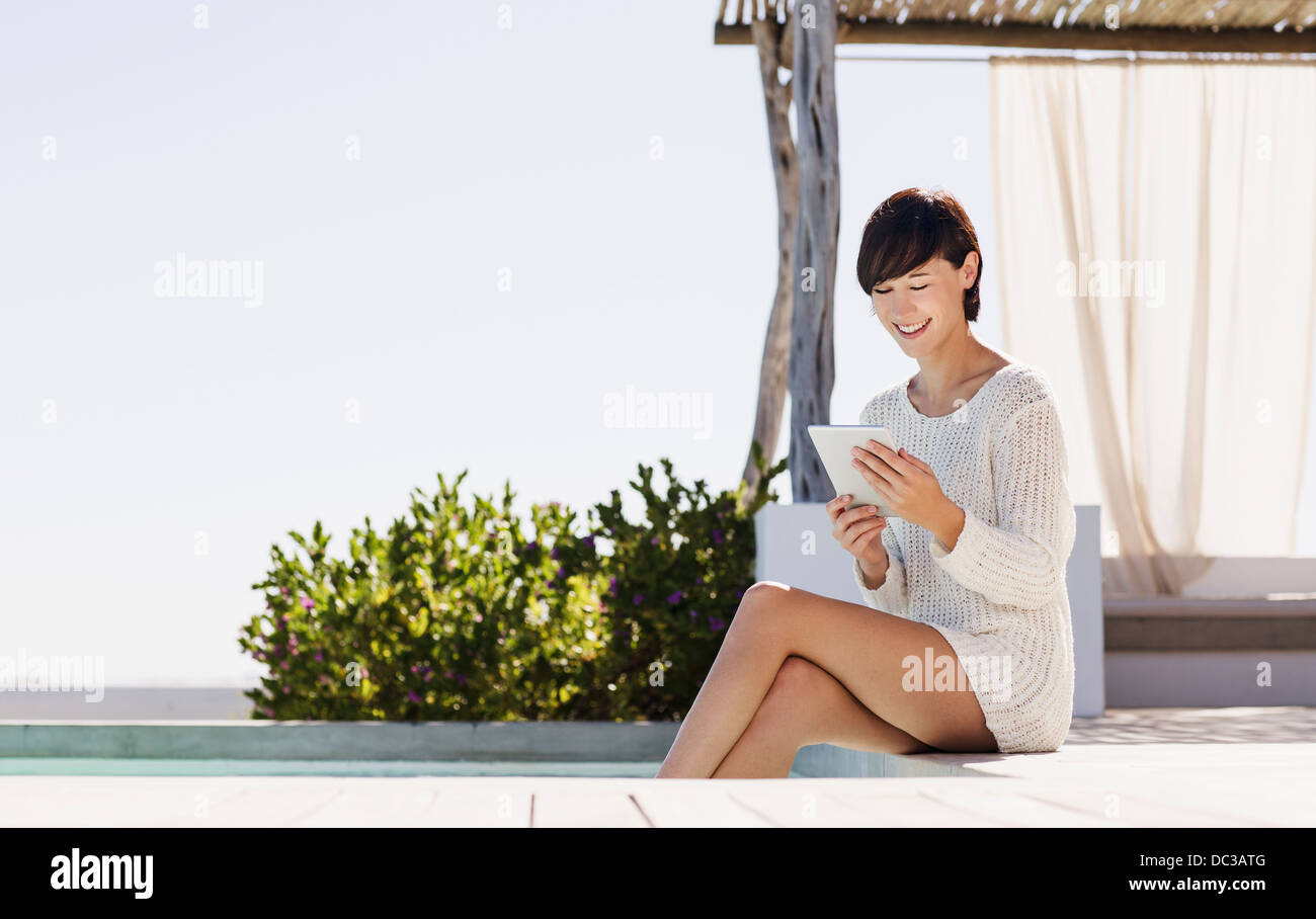 Smiling woman using digital tablet at poolside Banque D'Images