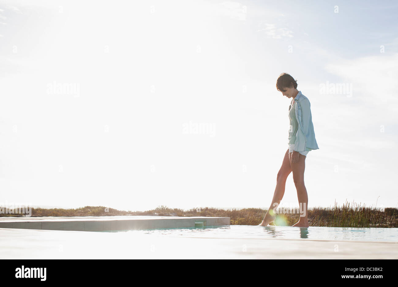 Femme trempant toe in swimming pool Banque D'Images