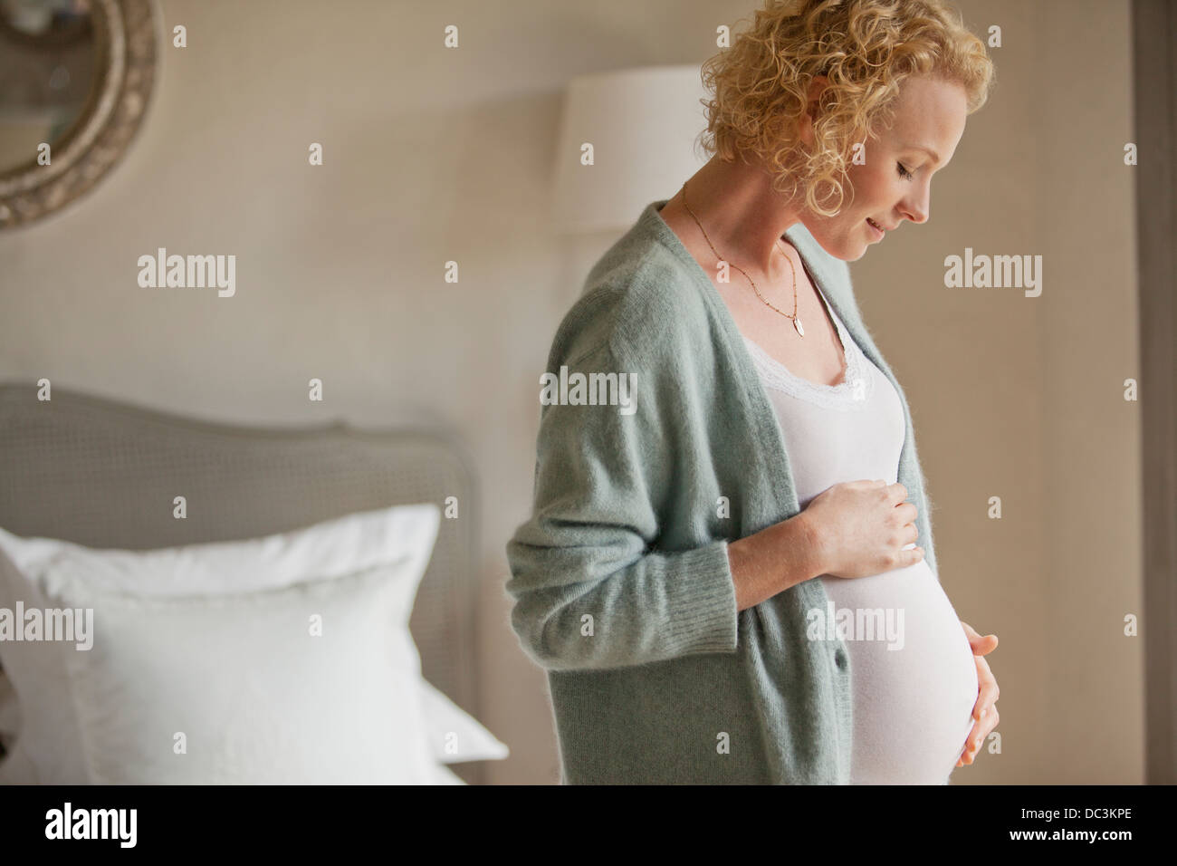 Smiling pregnant woman touching stomach dans la chambre Banque D'Images