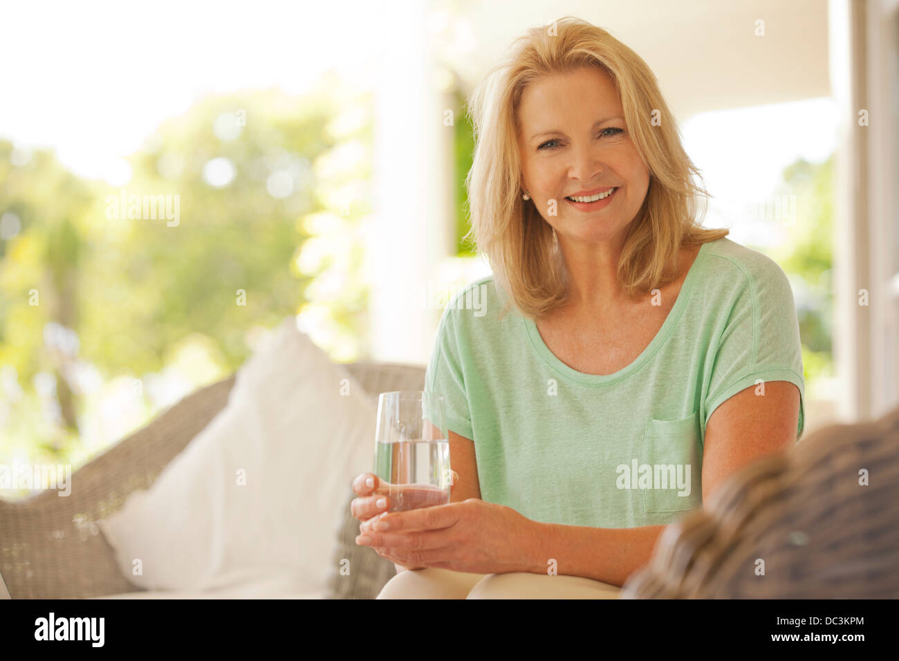Portrait of smiling woman drinking water on patio Banque D'Images