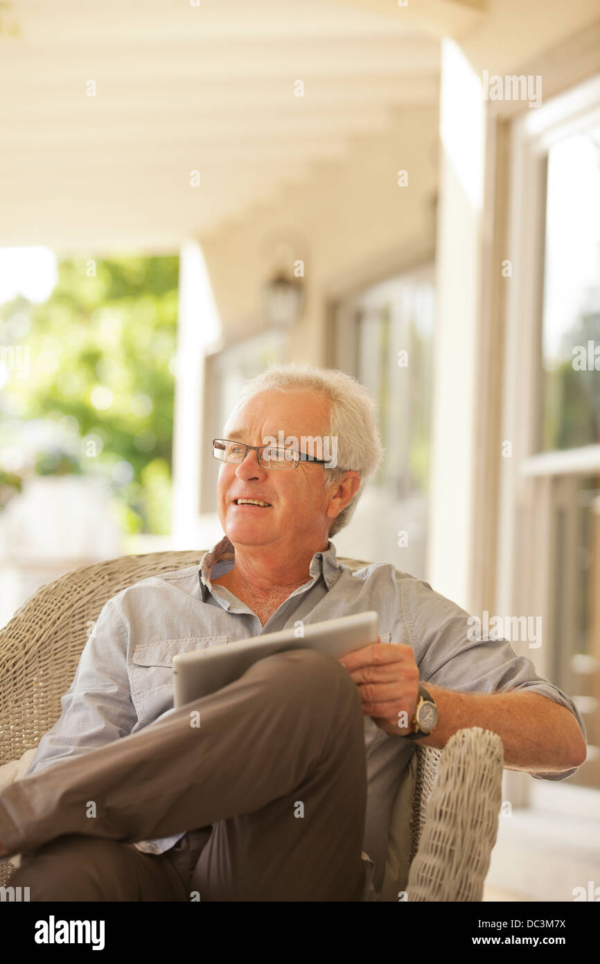 Smiling senior man using digital tablet on porch Banque D'Images