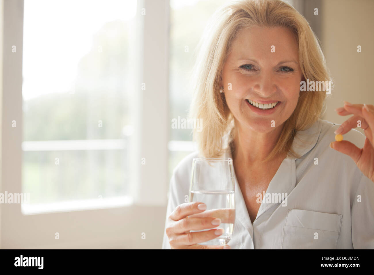 Portrait of smiling woman holding pill et verre de l'eau Banque D'Images