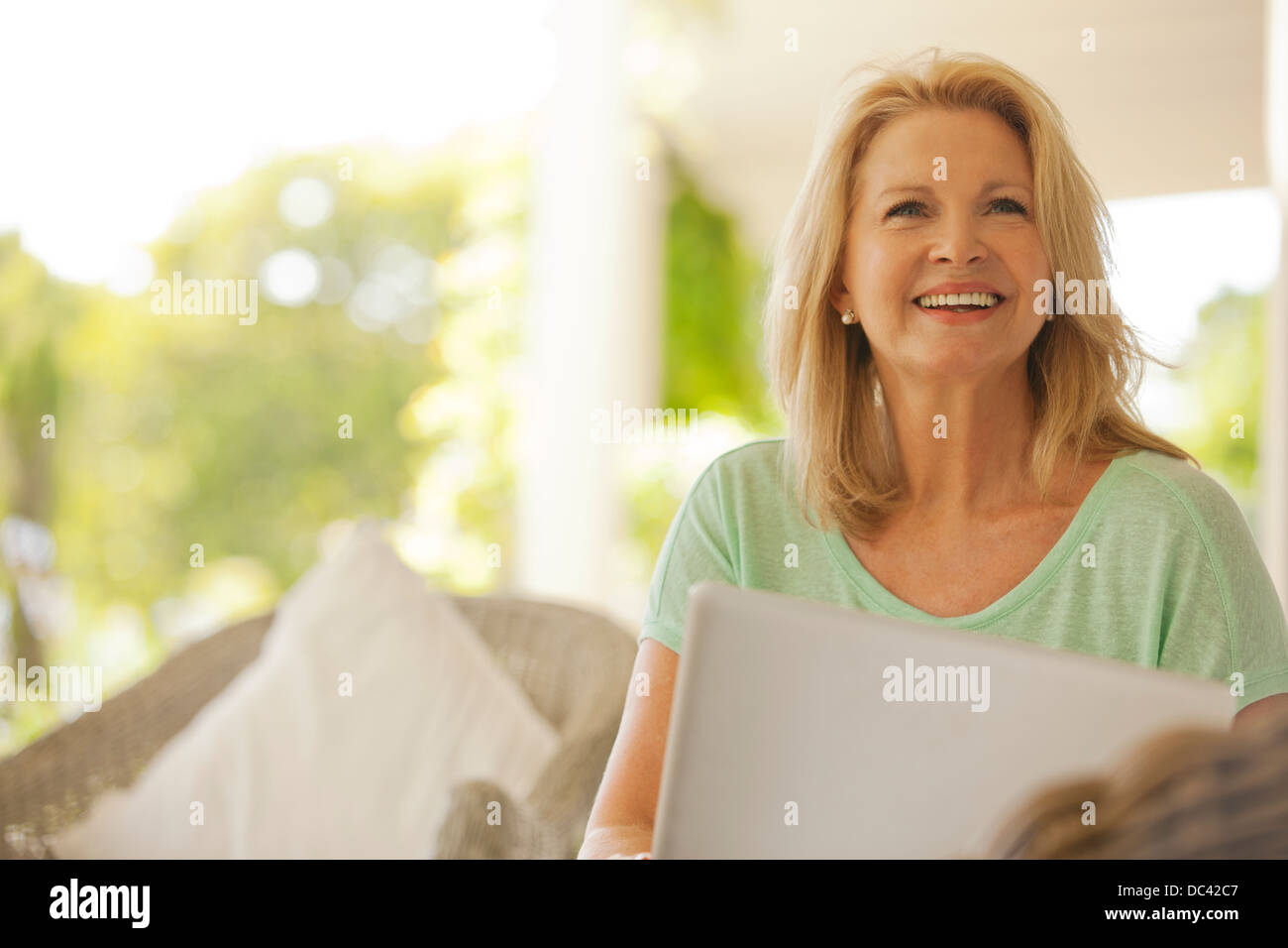 Smiling woman using laptop on patio Banque D'Images
