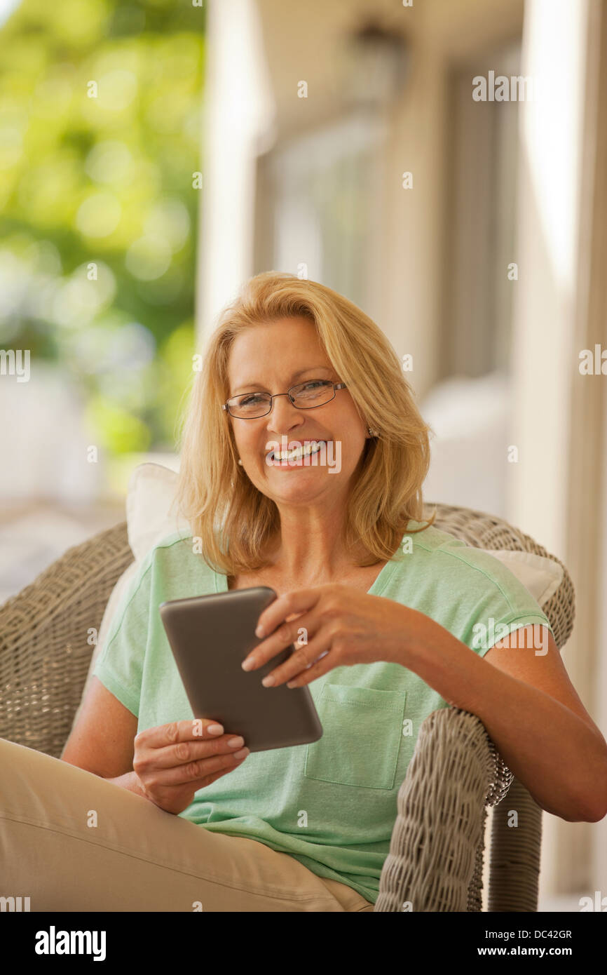Portrait of smiling woman using digital tablet on porch Banque D'Images