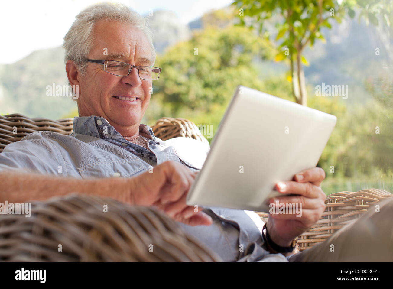 Smiling senior man using digital tablet on patio Banque D'Images