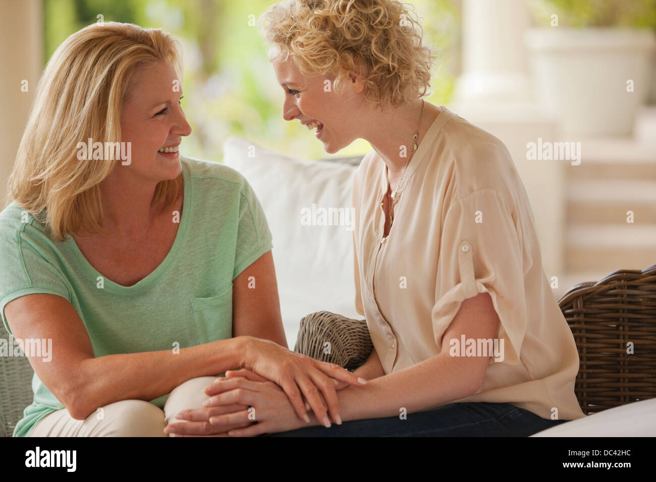 Smiling mother and daughter holding hands on porch Banque D'Images