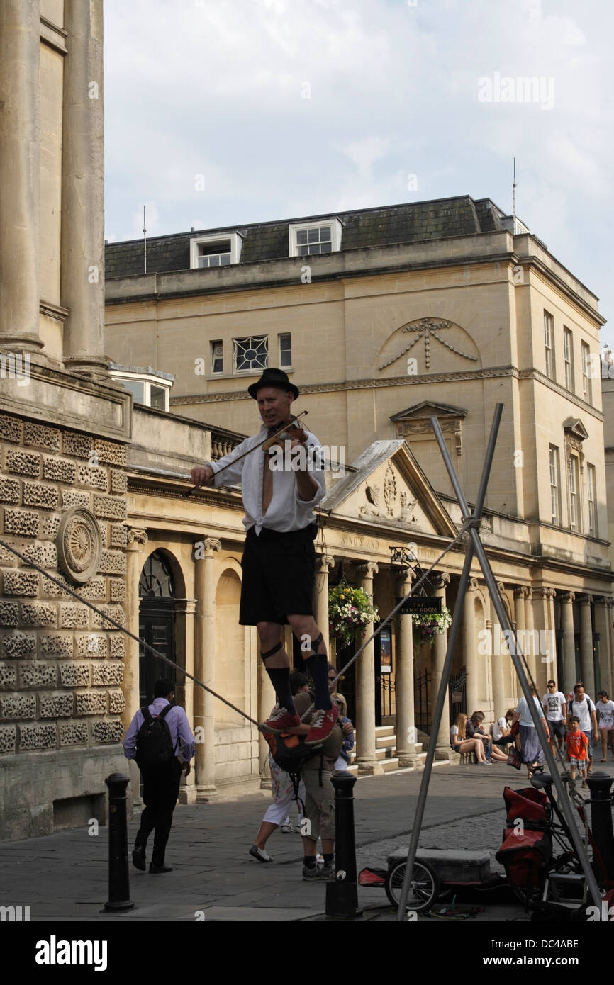 Homme marchant sur la corde raide tout en jouant du violon, Busker / Street Entertainer dans le centre-ville de Bath en Angleterre Banque D'Images