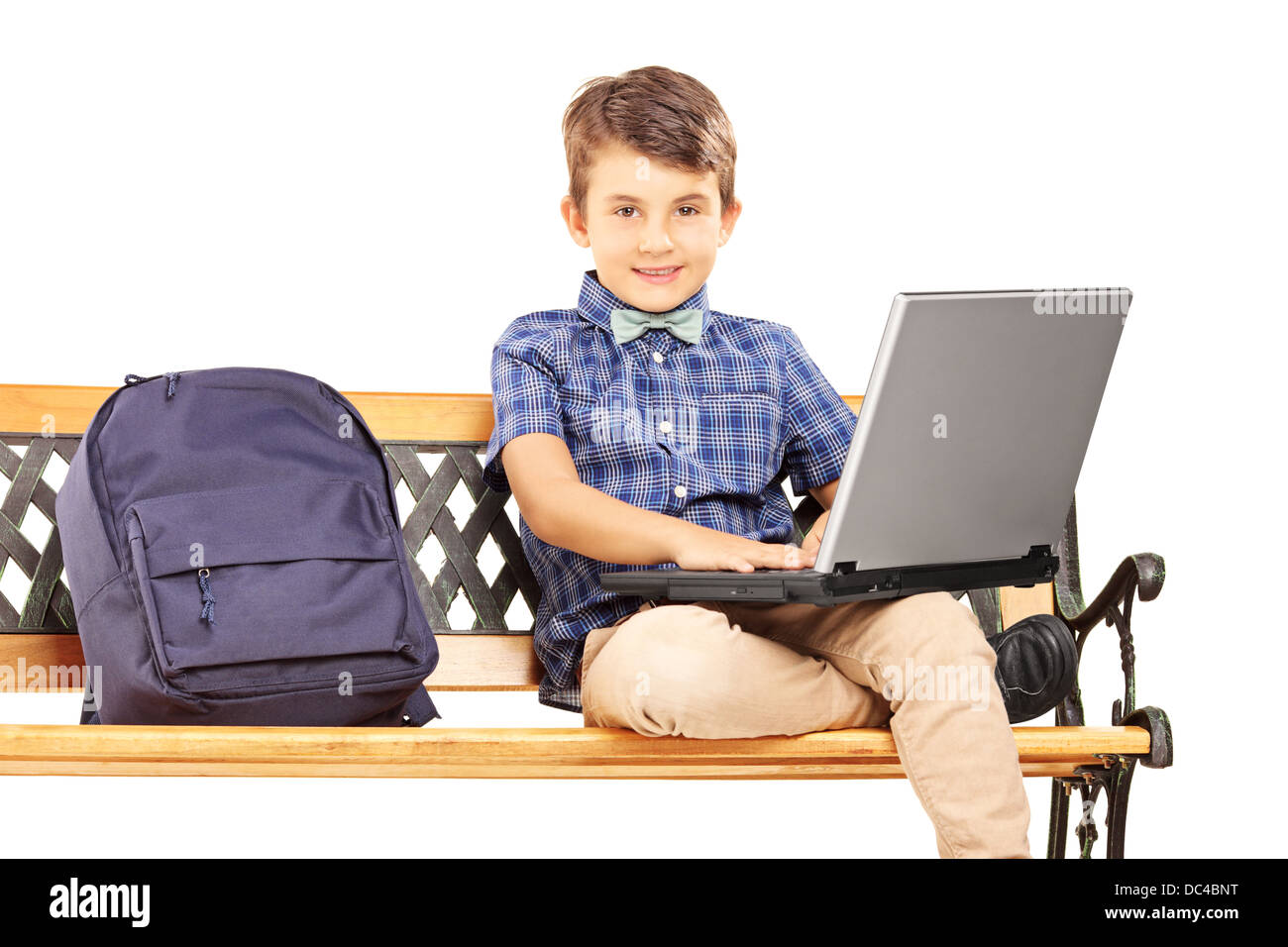 Écolier assis sur un banc en bois avec sac à côté de lui et de travailler sur un ordinateur portable Banque D'Images