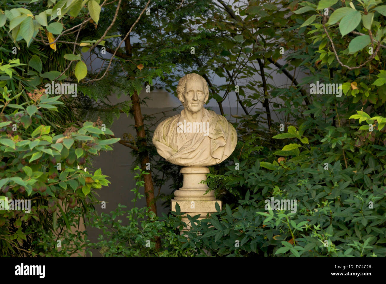 Caché sous le feuillage de la square Honoré-Champion à Paris 6ème Arrdt, le buste de pierre de Montesquieu . Banque D'Images