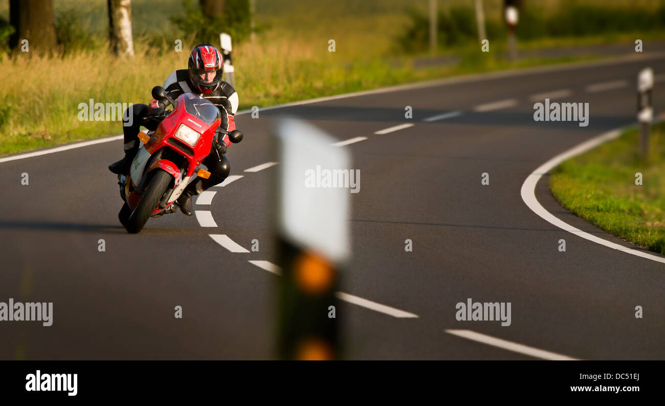 Motocycliste sur sa Ducati dans une courbe sur une route rurale Banque D'Images