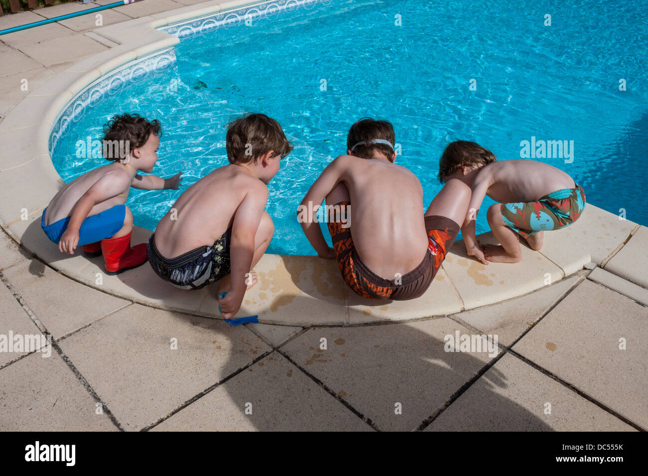 4 jeunes garçons au bord de la piscine Banque D'Images