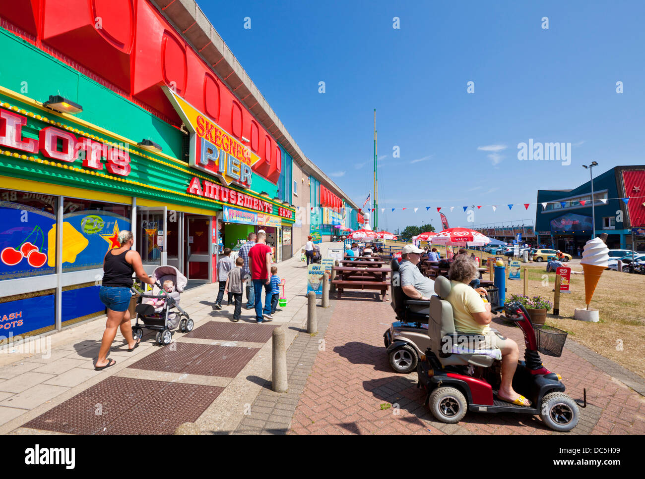 Les touristes handicapés assis devant l'entrée de jetée de Skegness Amusement arcade Lincolnshire england UK GB EU Europe Banque D'Images