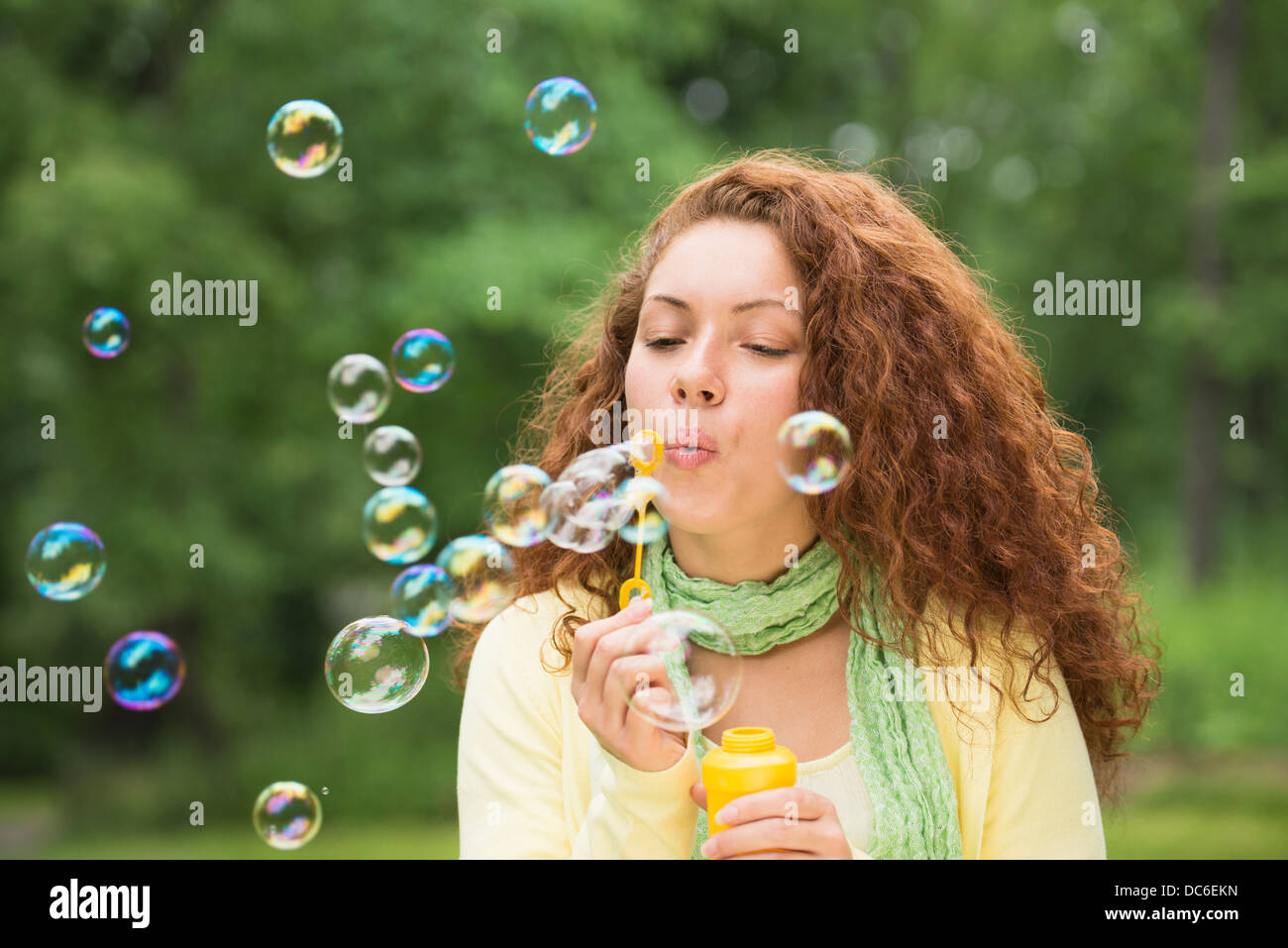 Young woman blowing bubbles in park Banque D'Images