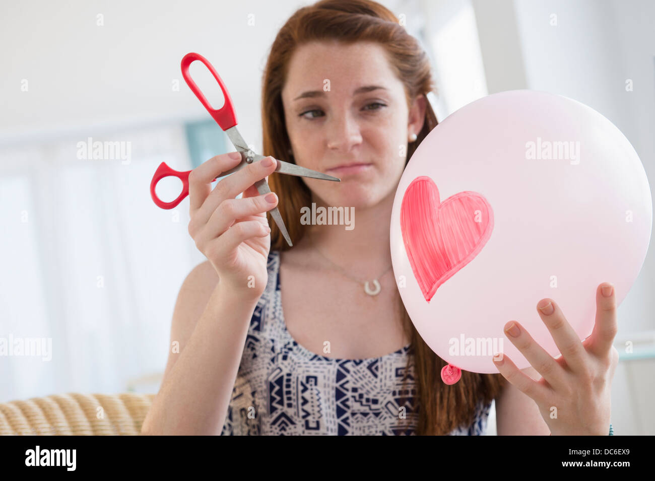 Teenage girl (14-15) holding balloon et ciseaux Banque D'Images