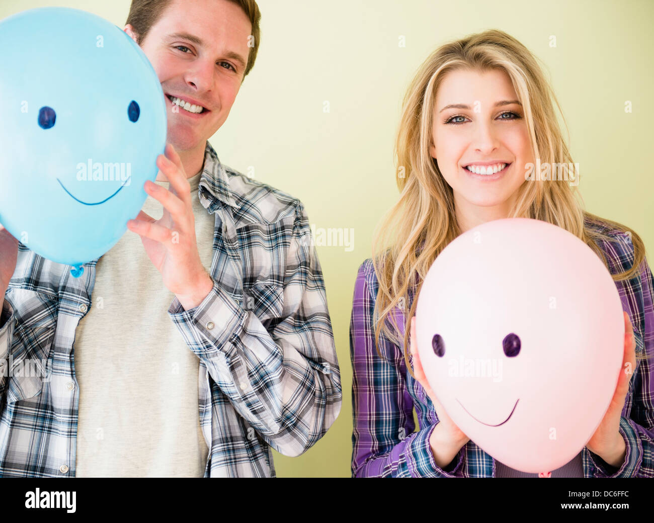 Studio shot of couple holding balloons avec smiley faces Banque D'Images