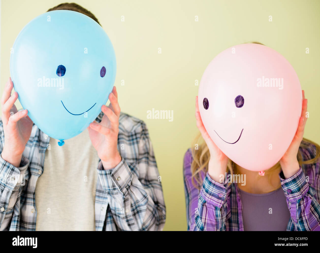 Studio shot of couple holding balloons avec smiley faces devant leurs chefs Banque D'Images