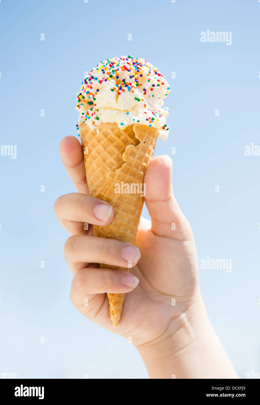 Girl (8-9) holding ice cream against blue sky Banque D'Images