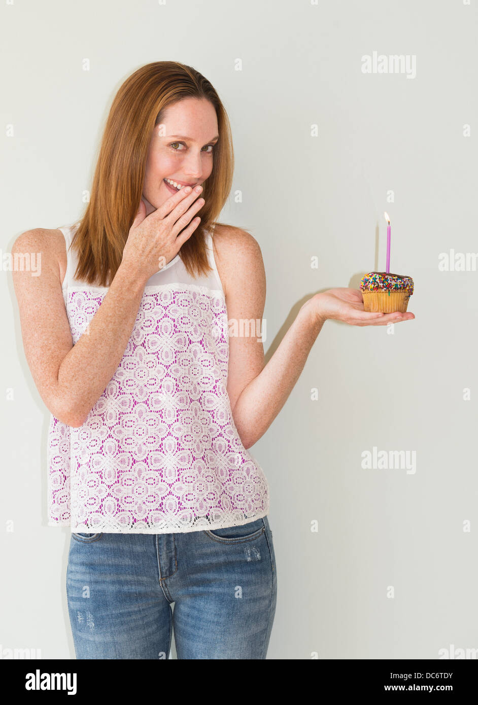 Studio portrait of woman holding birthday cupcake Banque D'Images