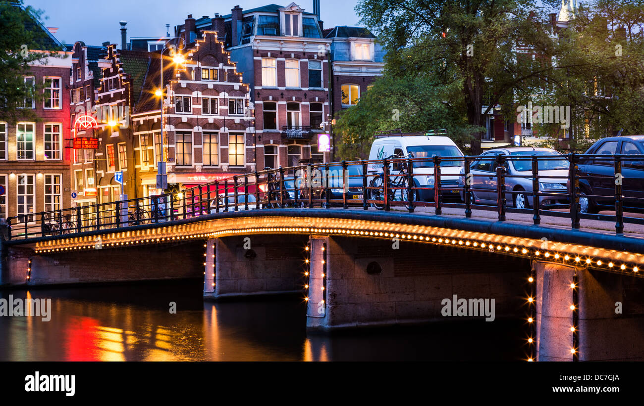 Halvemaans bridge d'Amsterdam, éclairé, avec des maisons typiquement néerlandais dans l'arrière-plan Banque D'Images