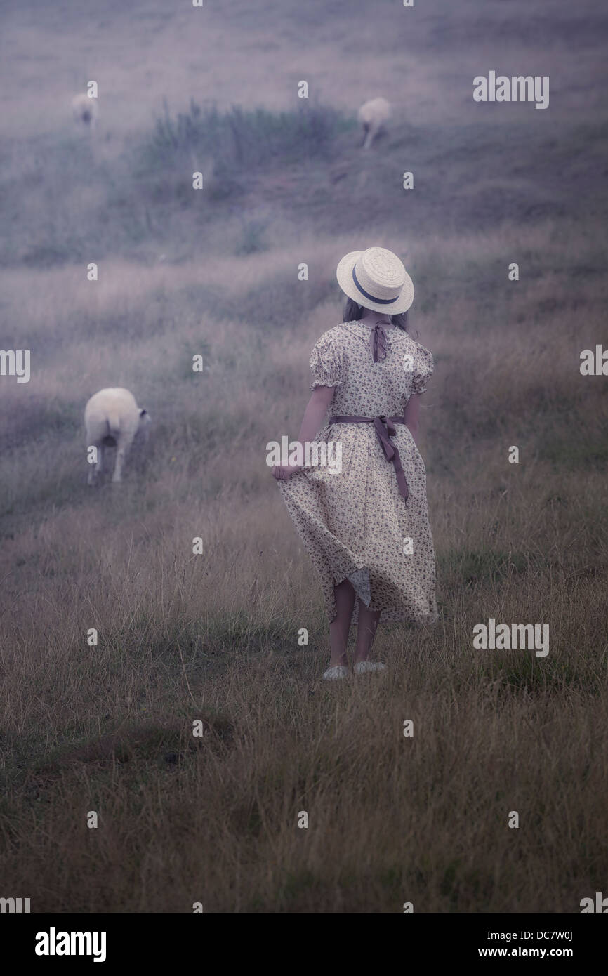 Une fille dans une robe vintage sur une prairie avec moutons Banque D'Images