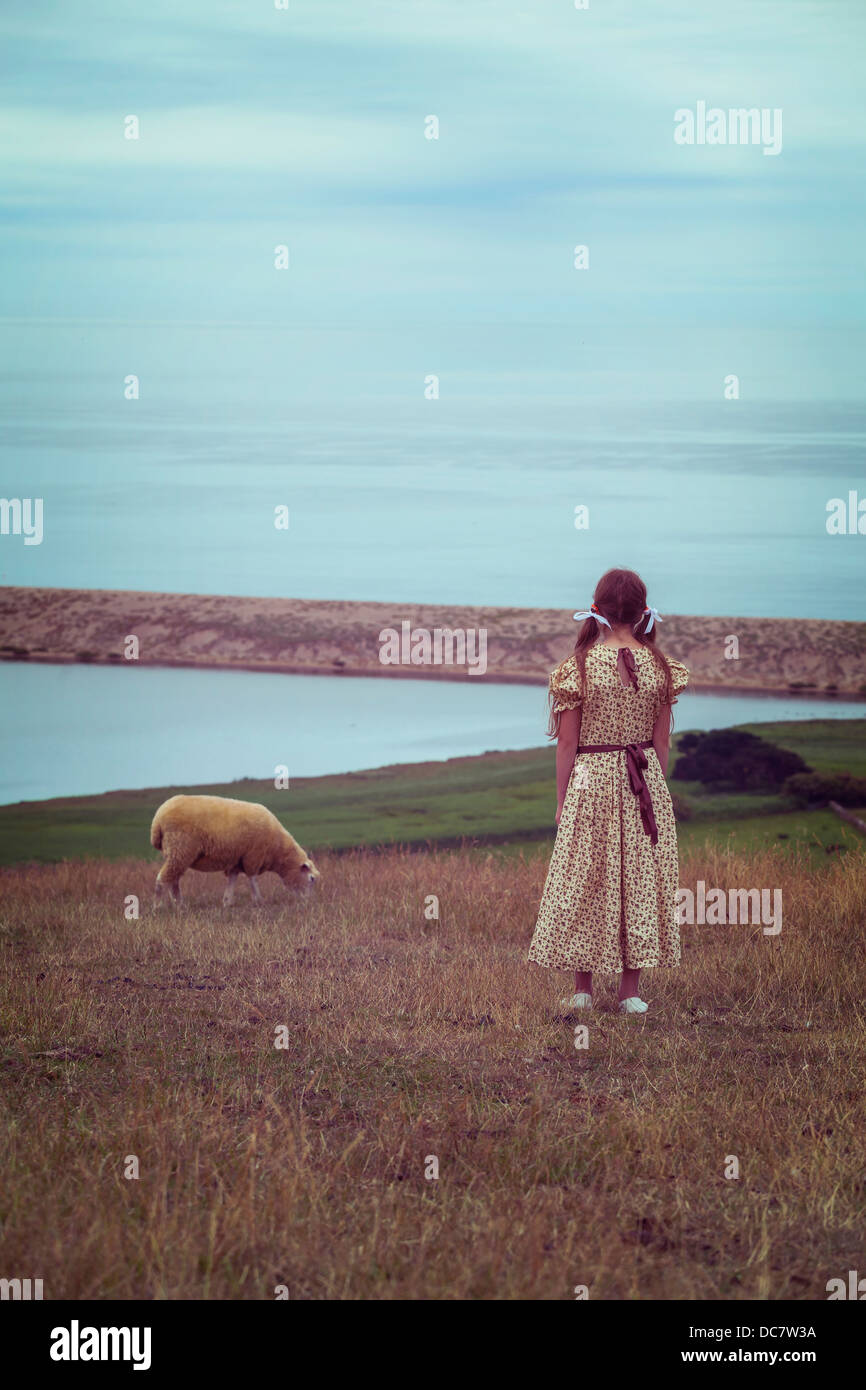 Une fille dans une robe vintage sur une prairie avec un mouton Banque D'Images