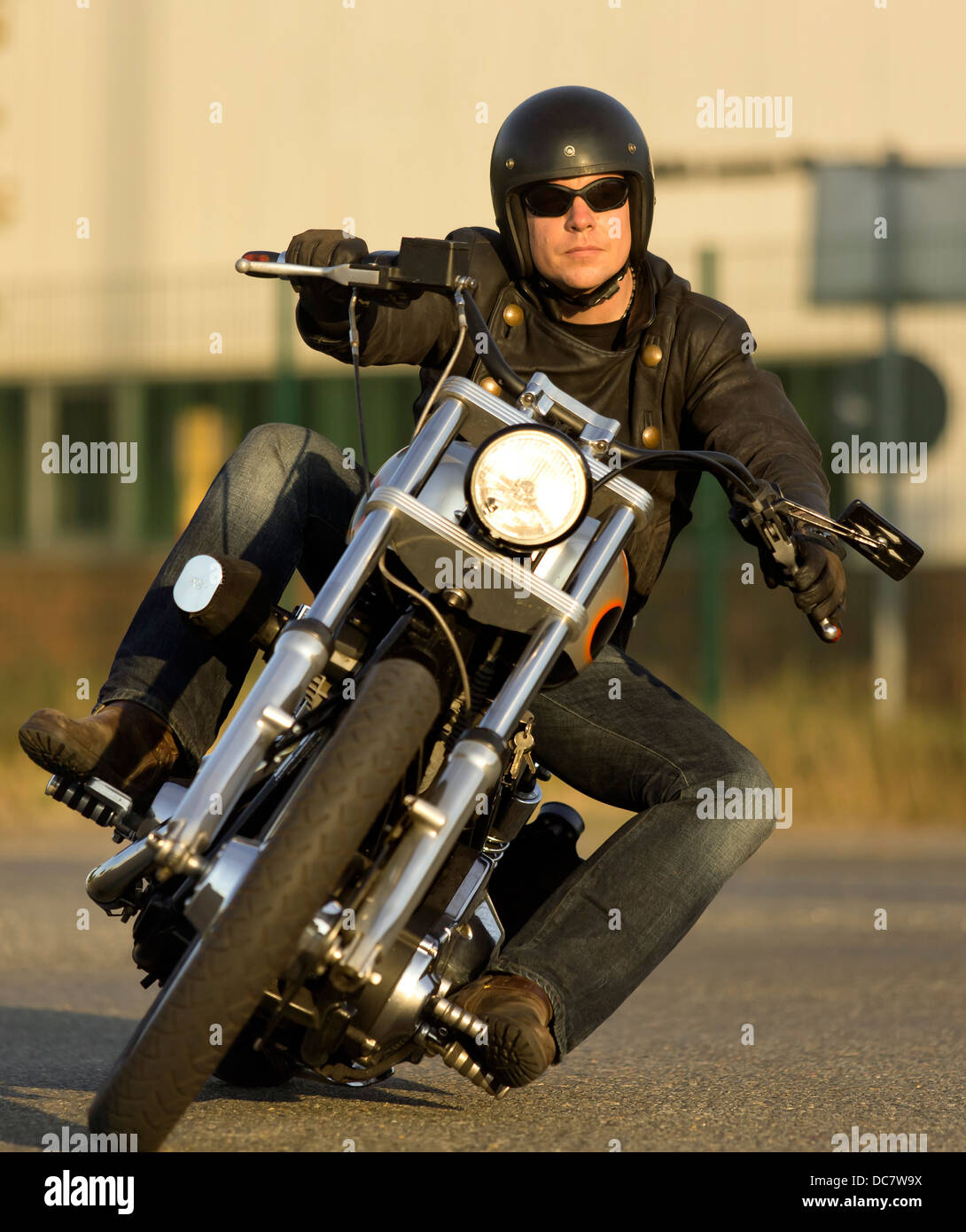 Jeune homme portant des vêtements en cuir avec sa Harley Davidson Banque D'Images